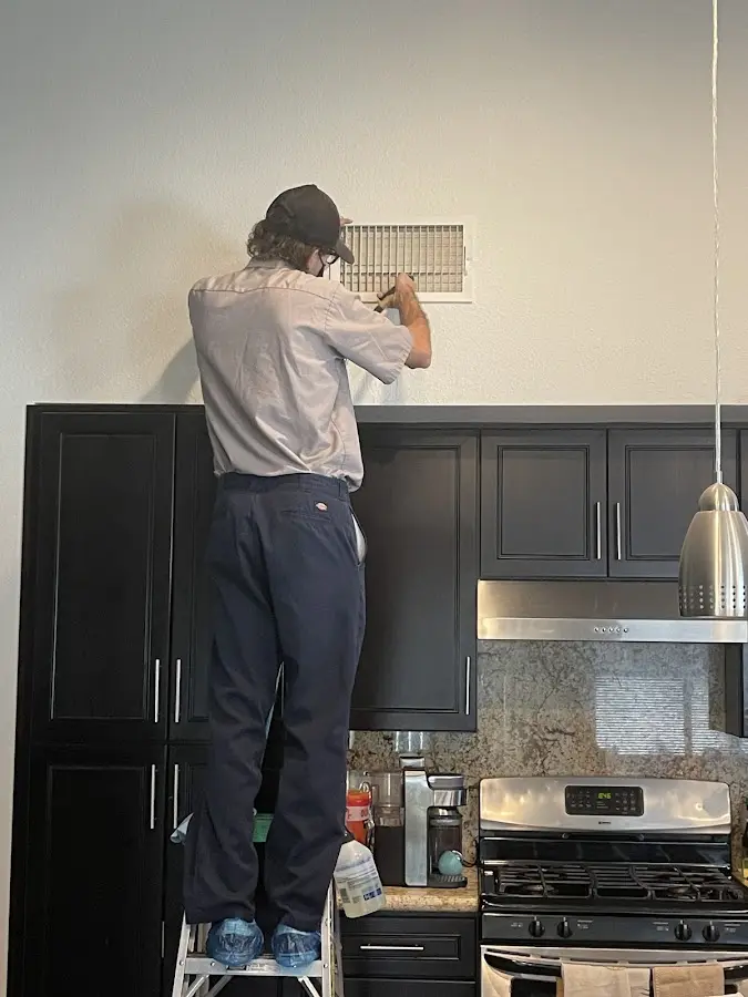 Technician inspecting an air vent during HVAC service in Burien